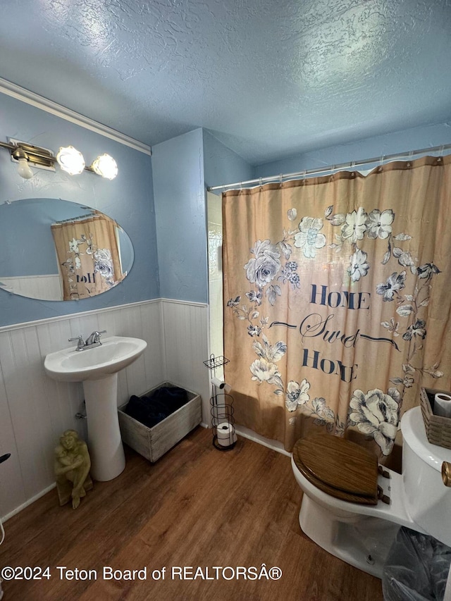 bathroom with a textured ceiling, hardwood / wood-style floors, and toilet