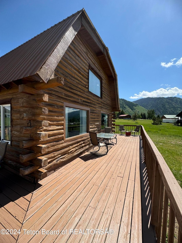 wooden deck featuring a mountain view and a lawn