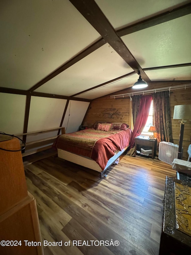 bedroom featuring wooden walls, vaulted ceiling, hardwood / wood-style floors, and a wood stove