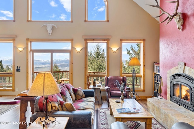 living room featuring a mountain view, wood-type flooring, a towering ceiling, and a tile fireplace