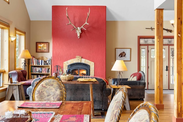 living room with wood-type flooring, vaulted ceiling, and a tiled fireplace