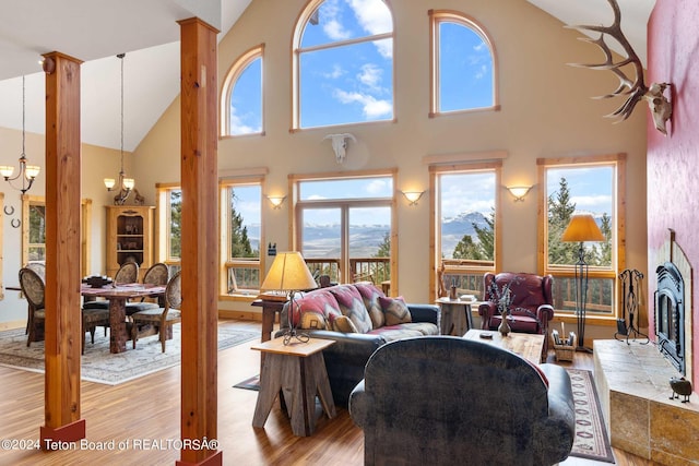 living room with a tile fireplace, high vaulted ceiling, a chandelier, and light wood-type flooring