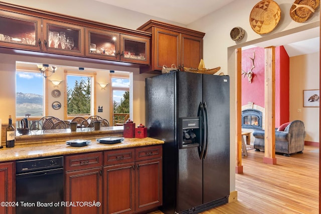 kitchen featuring black fridge, light wood-type flooring, light stone counters, and a wealth of natural light