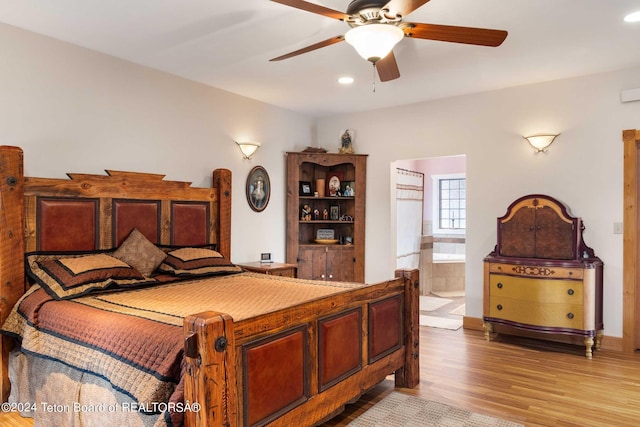 bedroom featuring ceiling fan, light hardwood / wood-style floors, and ensuite bath