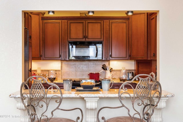 kitchen featuring light stone countertops, a kitchen breakfast bar, and backsplash