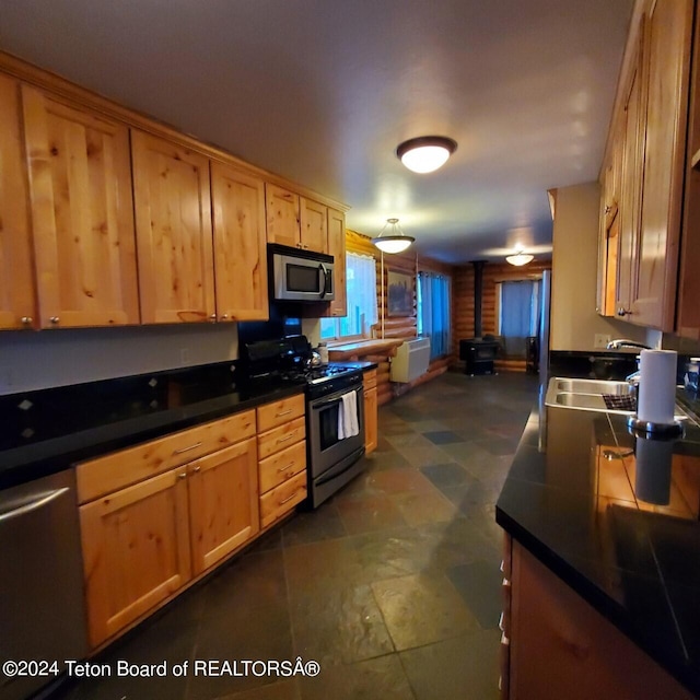 kitchen featuring a wood stove, sink, and appliances with stainless steel finishes