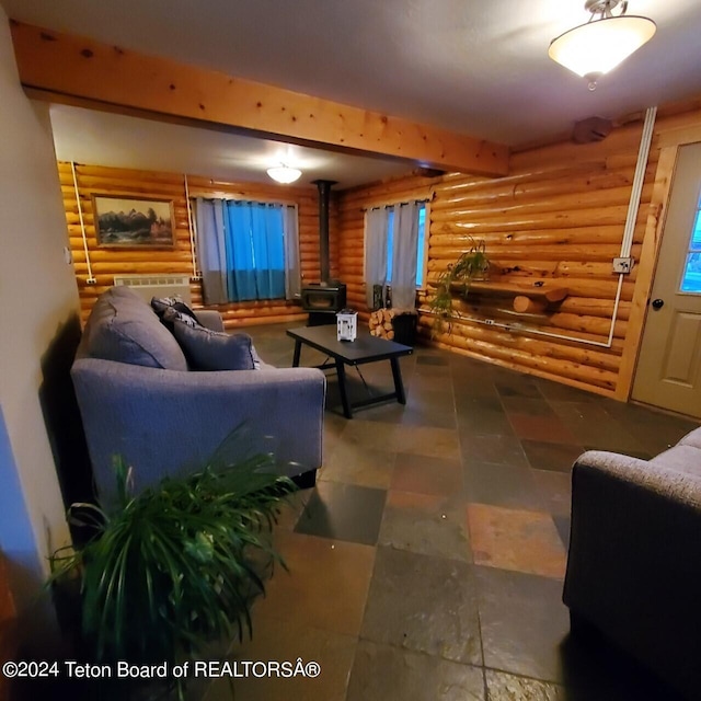 living room with a wood stove, rustic walls, and beam ceiling