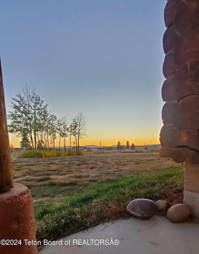 yard at dusk featuring a rural view