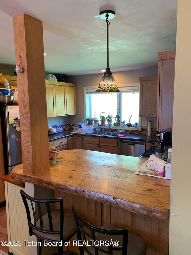 955 Budge Dr Unit 4, Jackson, WY 83001 - kitchen with a sink, stainless steel appliances, wood counters, a breakfast bar area, and a peninsula