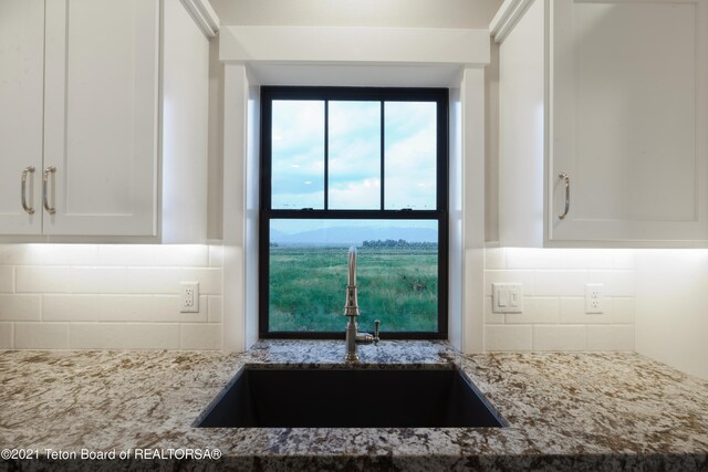 1845 S 5000 W, Driggs, ID 83422 - kitchen featuring backsplash, a sink, white cabinets, and light stone counters