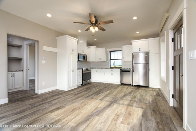 1845 S 5000 W, Driggs, ID 83422 - kitchen with white cabinetry, decorative backsplash, appliances with stainless steel finishes, ceiling fan, and light wood-type flooring