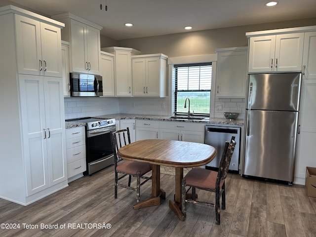 1845 S 5000 W, Driggs, ID 83422 - kitchen featuring wood finished floors, appliances with stainless steel finishes, white cabinets, backsplash, and a sink