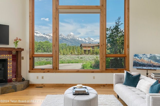 living room with a tiled fireplace, a mountain view, and hardwood / wood-style flooring