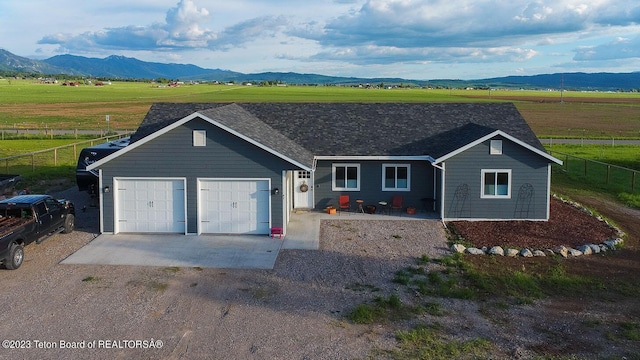 single story home featuring a garage, a mountain view, and a rural view