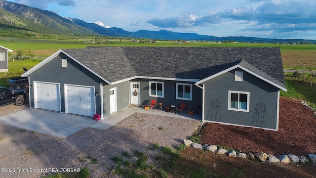 ranch-style home with a garage, a mountain view, and a patio area