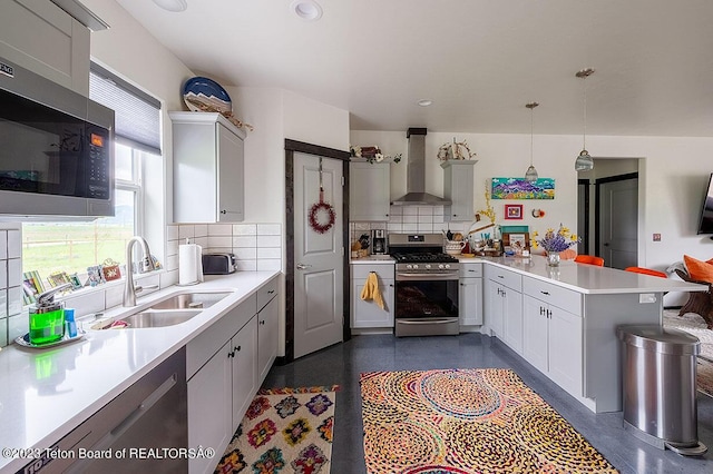 kitchen with appliances with stainless steel finishes, sink, backsplash, hanging light fixtures, and wall chimney exhaust hood