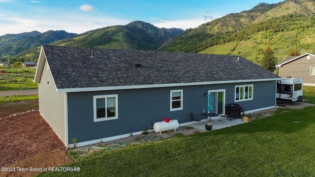 back of property featuring a yard, a mountain view, and a patio area