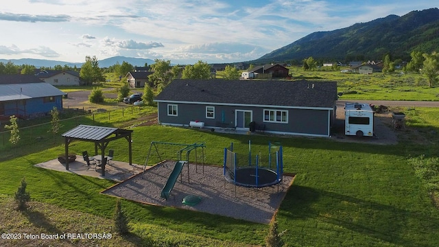 back of house with a patio area, a gazebo, a trampoline, a yard, and a mountain view