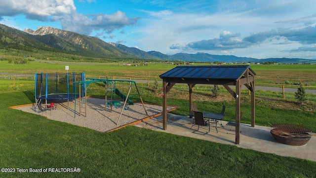 view of play area with a rural view, a mountain view, a fire pit, and a patio