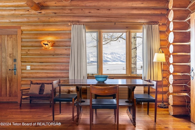 dining room with a mountain view, hardwood / wood-style flooring, and rustic walls