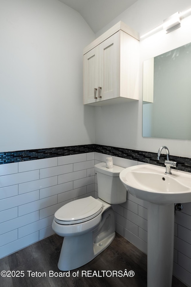 bathroom featuring wood-type flooring, lofted ceiling, tile walls, and toilet