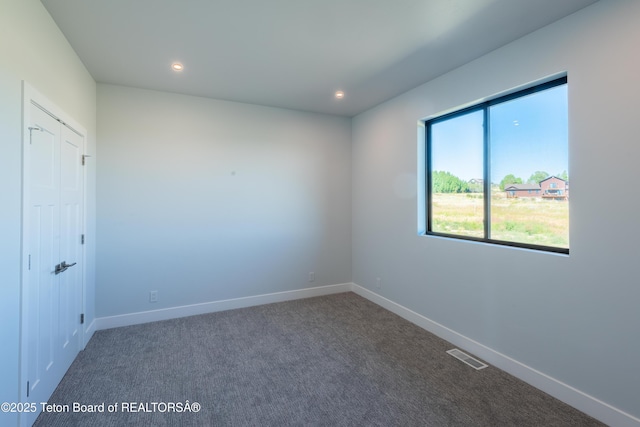 unfurnished room with dark colored carpet