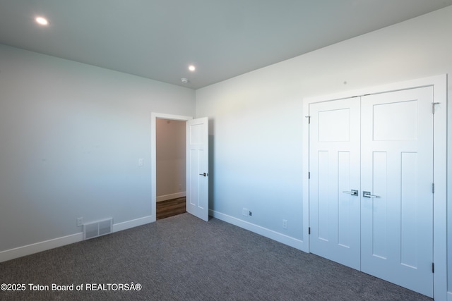 unfurnished bedroom with dark carpet and a closet