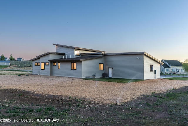 back house at dusk featuring cooling unit