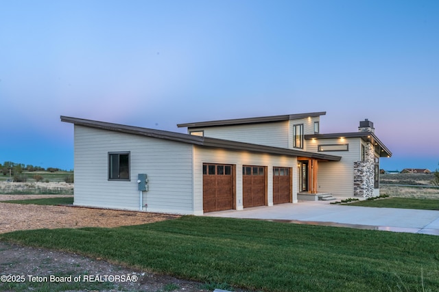 property exterior at dusk with a garage and a lawn