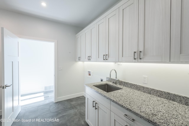 kitchen featuring white cabinetry, sink, and light stone counters