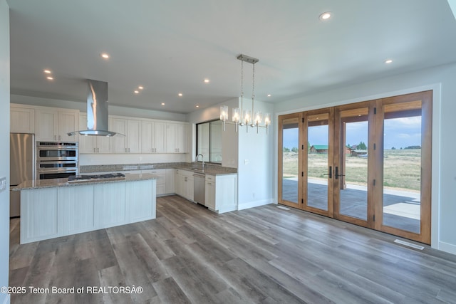 kitchen featuring sink, a center island, appliances with stainless steel finishes, island exhaust hood, and white cabinets