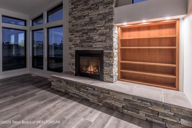 unfurnished living room with hardwood / wood-style flooring and a stone fireplace