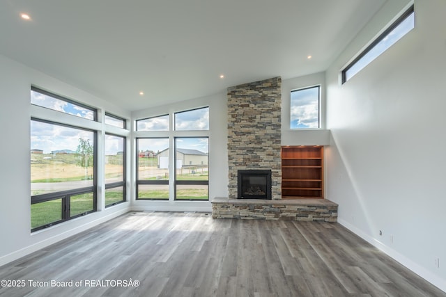 unfurnished living room featuring hardwood / wood-style flooring, a fireplace, and a healthy amount of sunlight