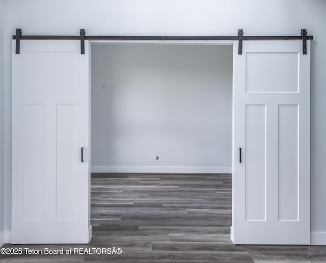 unfurnished room with dark hardwood / wood-style floors and a barn door