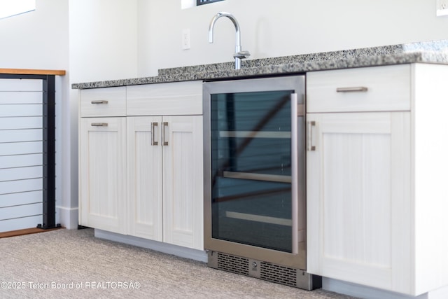 details with sink, light carpet, dark stone counters, beverage cooler, and white cabinets