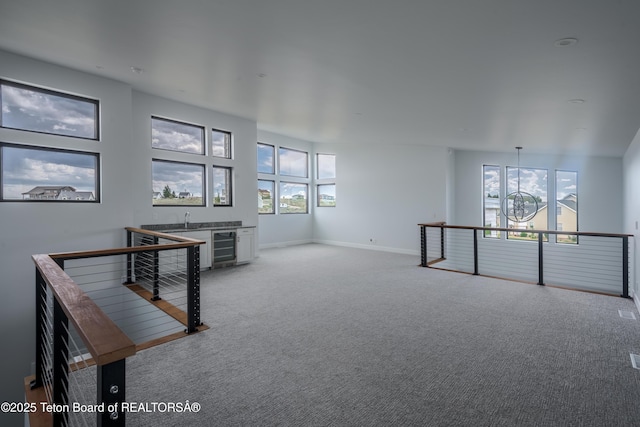 interior space with bar, a wealth of natural light, beverage cooler, and carpet flooring