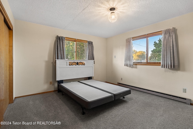 unfurnished bedroom with baseboard heating, a textured ceiling, and multiple windows