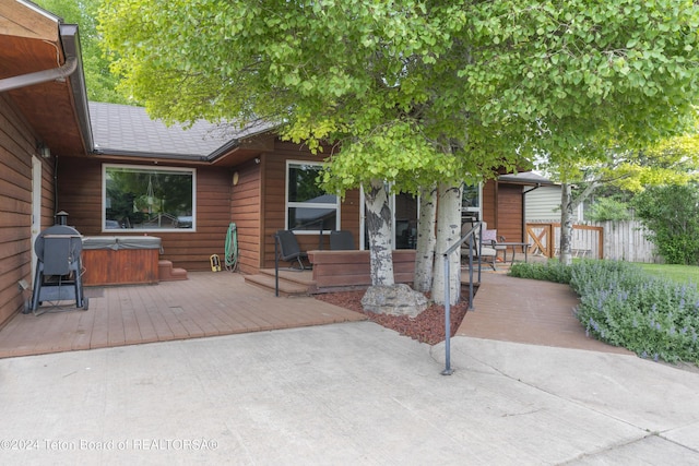 view of front of house featuring a patio, a wooden deck, and a hot tub