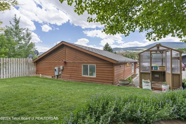 view of home's exterior with a lawn, a mountain view, and an outdoor structure