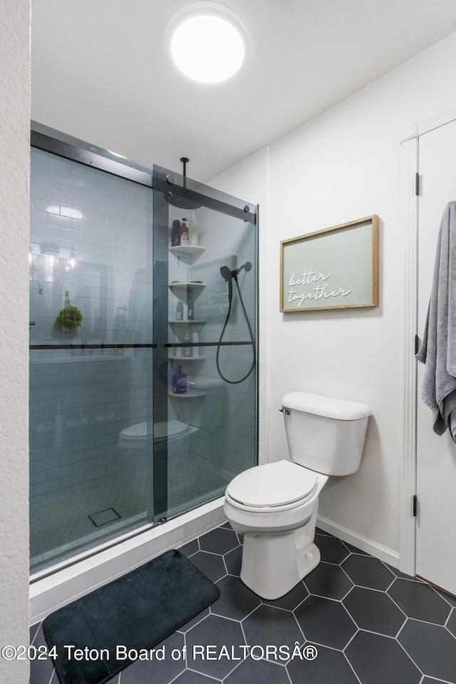 bathroom with tile patterned floors, toilet, and a shower with shower door