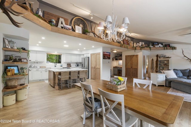 dining area with ceiling fan with notable chandelier, light hardwood / wood-style floors, and track lighting