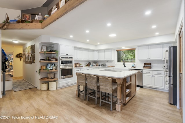 kitchen featuring a center island, stainless steel appliances, a kitchen breakfast bar, light hardwood / wood-style flooring, and white cabinets