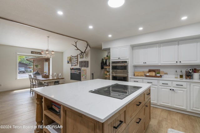 kitchen with white cabinetry, a kitchen island, pendant lighting, and an inviting chandelier