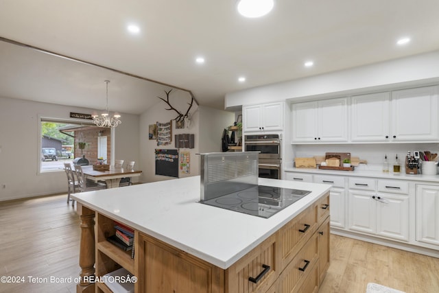 kitchen featuring decorative light fixtures, a kitchen island, and white cabinetry