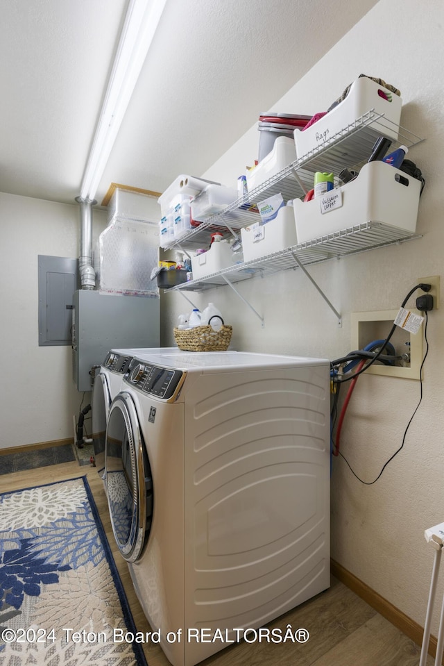 clothes washing area with washer and clothes dryer, hardwood / wood-style floors, and electric panel