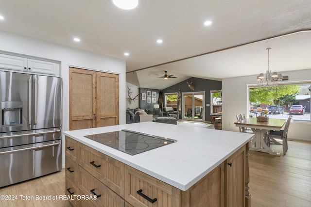 kitchen with white cabinets, ceiling fan with notable chandelier, stainless steel fridge, black electric cooktop, and a kitchen island