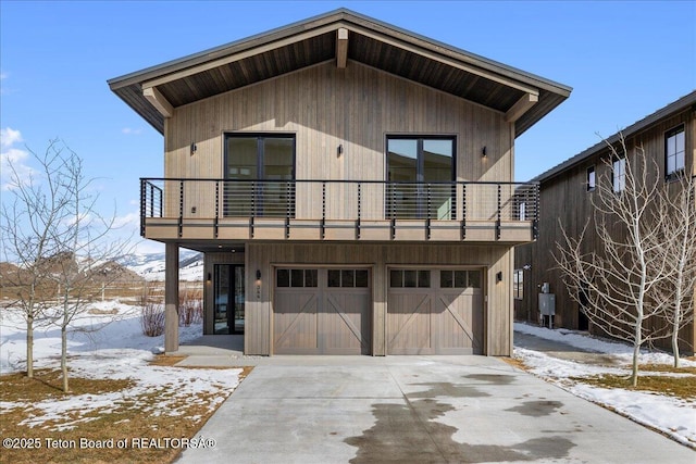 view of front of home with concrete driveway, a balcony, and an attached garage