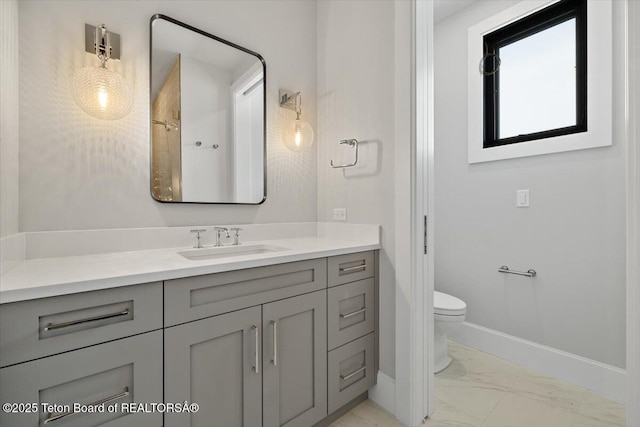 bathroom featuring toilet, marble finish floor, baseboards, and vanity