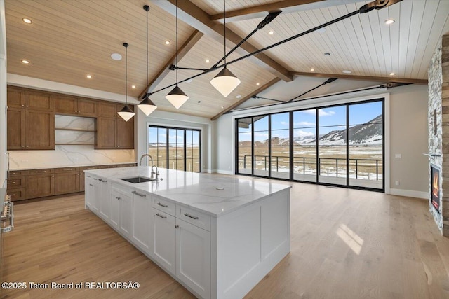 kitchen with lofted ceiling with beams, open shelves, light wood finished floors, and a sink