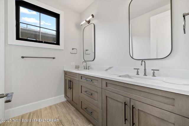 bathroom featuring a sink, baseboards, and double vanity